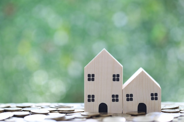 MortgageModel house and stack of coins money on natural green background