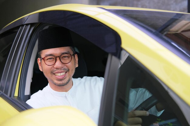 Moslem Asian man sitting in car driver seat smiling happy at the camera