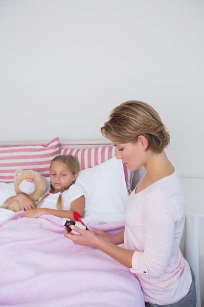 Mother about to give medicine to sick daughter