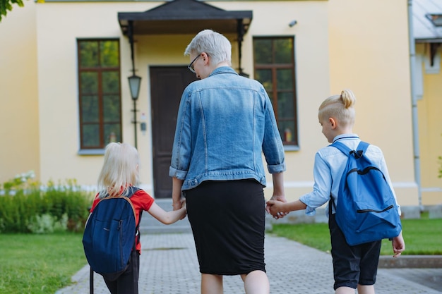 Mother accompanies children to school holding hands