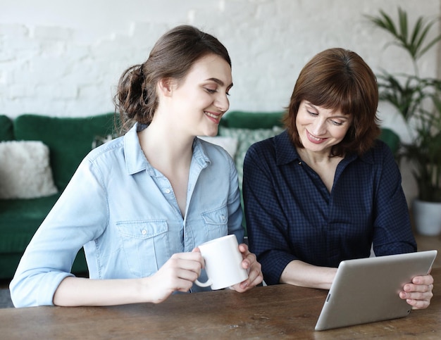 Mother and adult daughter using tablet computer at home