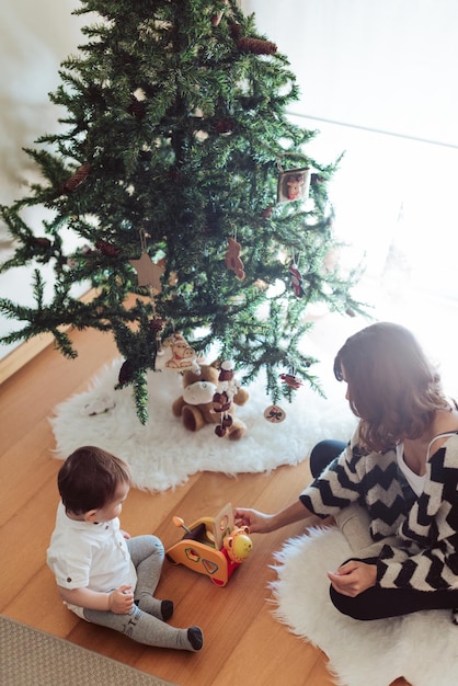 Mother and baby decorating and playing around the Christmas Tree