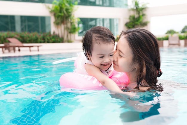 Mother and baby girl having fun in the pool. Summer holidays and vacation concept