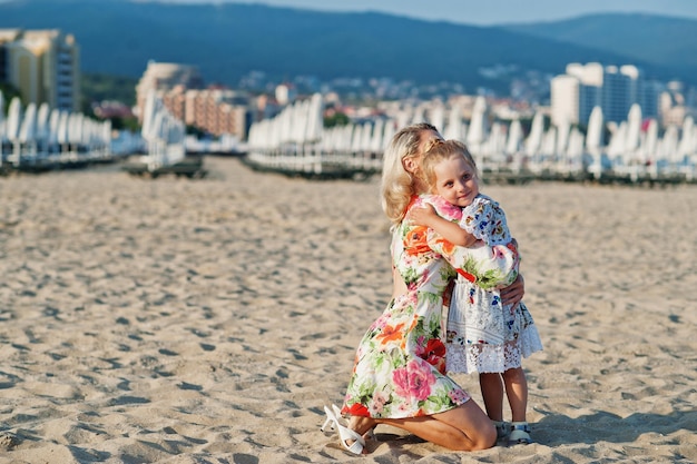 Mother and beautiful daughter having fun on the beach Portrait of happy woman with cute little girl on vacation