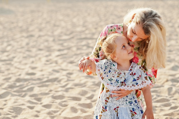 Mother and beautiful daughter having fun on the beach Portrait of happy woman with cute little girl on vacation