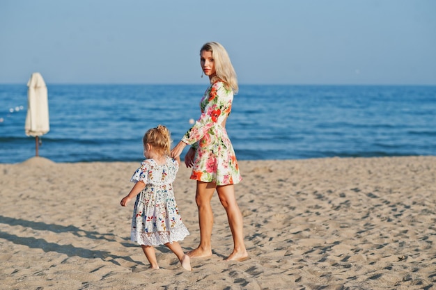 Mother and beautiful daughter having fun on the beach Portrait of happy woman with cute little girl on vacation