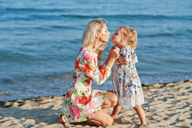 Mother and beautiful daughter having fun on the beach Portrait of happy woman with cute little girl on vacation