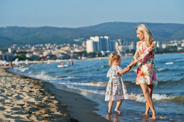 Mother and beautiful daughter having fun on the beach Portrait of happy woman with cute little girl on vacation