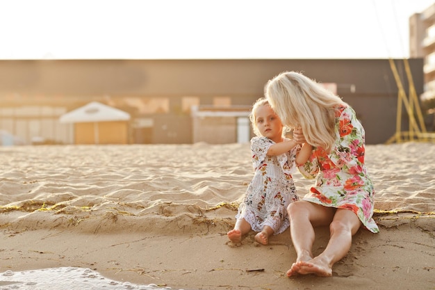 Mother and beautiful daughter having fun on the beach Portrait of happy woman with cute little girl on vacation