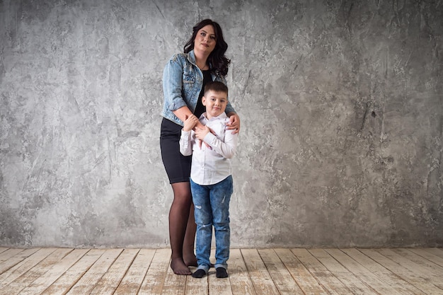 A mother in a black dress holds her son in her arms and sits on a high chair