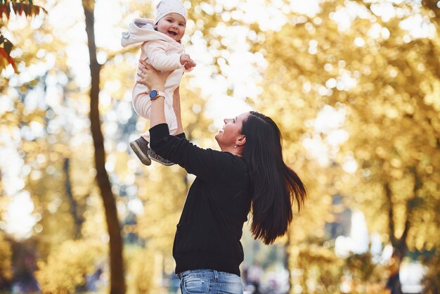 Mother in casual clothes with her child is in the beautiful autumn park.