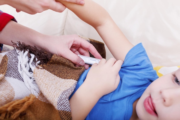 Mother checking the temperature of her ill baby with a thermometer.