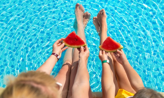 Mother and child eat watermelon by the pool