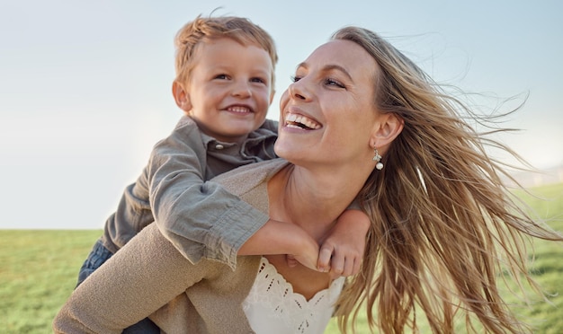 Mother child and happy piggyback in summer holiday and blue sky sunshine and play in a green park Happy mother kid and smile having fun outdoor for vacation with smile laugh and love in nature