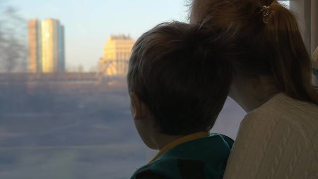 Mother and child looking out train window during the travel