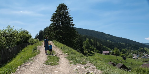 Mother and child walking on country road Countryside Walk on a Sunny day Blue sky hills and forest