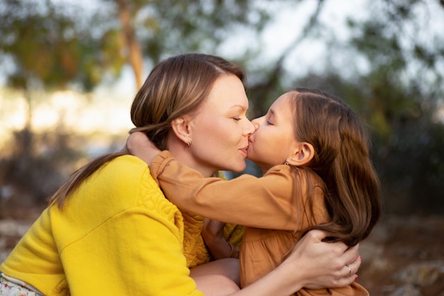 Mother and child walking and kissing in autumn park