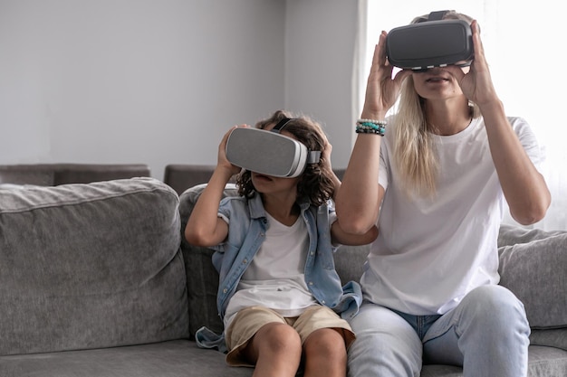 Mother and child wearing virtual reality headset vr glasses in living room at home having fun