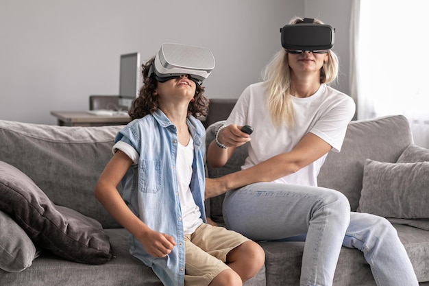 Mother and child wearing virtual reality headset vr glasses in living room at home having fun