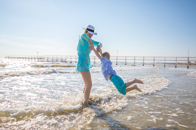 Mother and children are playing in the sea on the beach