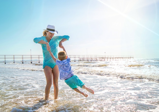 Mother and children are playing in the sea on the beach