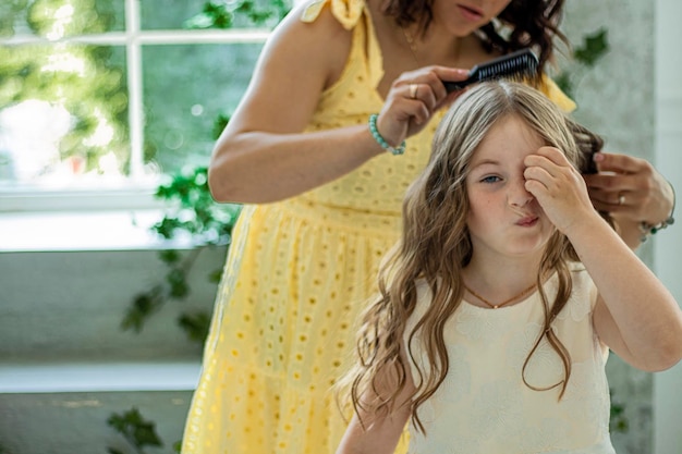 mother combs her daughter A girl with a displeased expres on her face Tangled baby hair