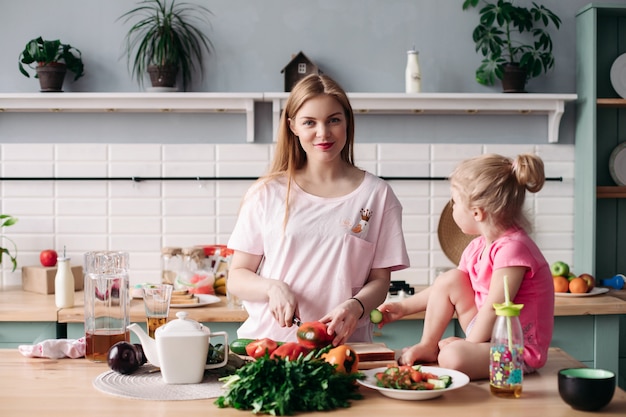 Mother cooking dinner on kitchen with her little cute kid