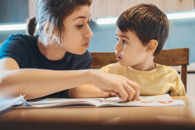 Mother correcting the error made by his son in home lessons studying doing homework online teaching