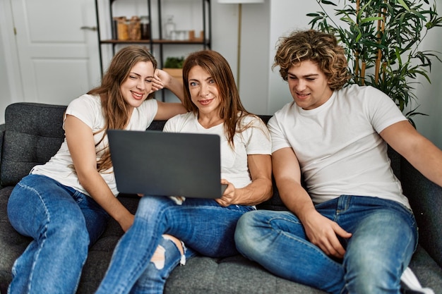 Mother and couple using laptop sitting on sofa at home