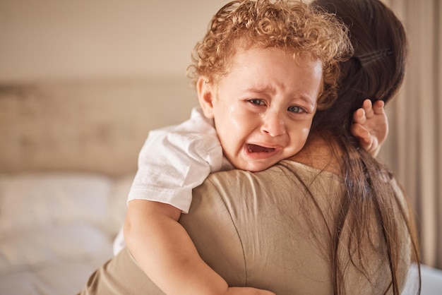 Mother and crying baby in a bedroom with portrait of sad son looking upset at nap time Children love and insomnia with baby boy comfort by loving parent embracing and bond in their home together