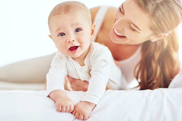 Mother and cute newborn baby boy bonding together as a family in the bedroom at home Happy smiling and carefree mom and son showing love and affection while relaxing on a bed in the morning