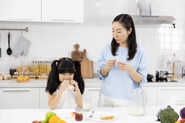 Mother and daughter are eating breakfast in the kitchen