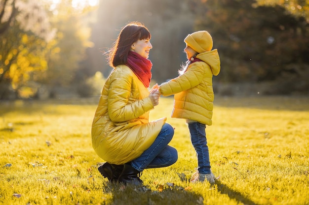 Mother and daughter in autumn yellow park.