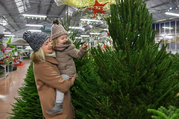 Mother and daughter choose a Christmas tree in a shop