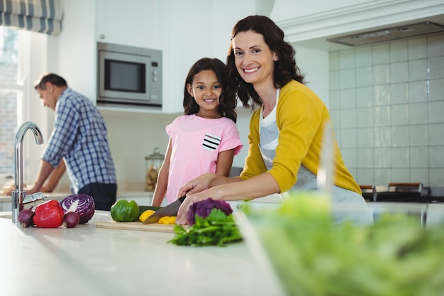 Mother and daughter chopping vegetables in kitchen