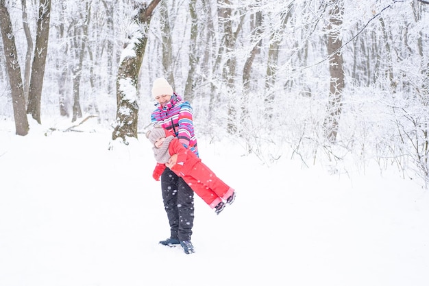 Mother and daughter in colorful clothes having fun on winter walk in nature