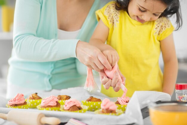 mother and daughter cooking cupcakes at home