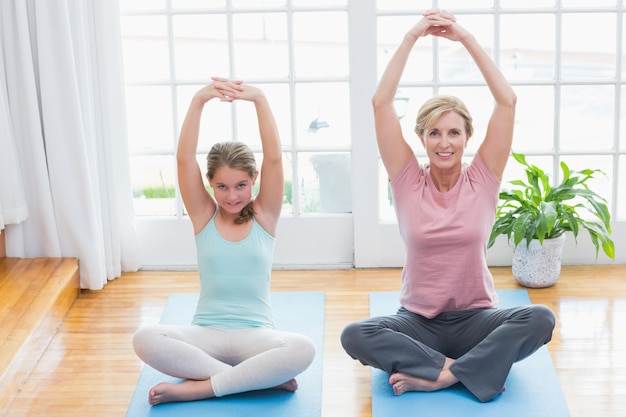 Mother and daughter doing yoga on fitness mat 