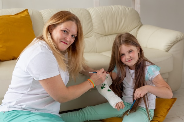 Mother and daughter drawing picture on bandage using paints play therapy concept