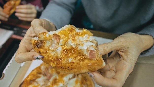 Mother and daughter eat pizza cheese four Close up of young woman eating pizza and chewing in outdoor restaurant Girl hands taking pieces pizza