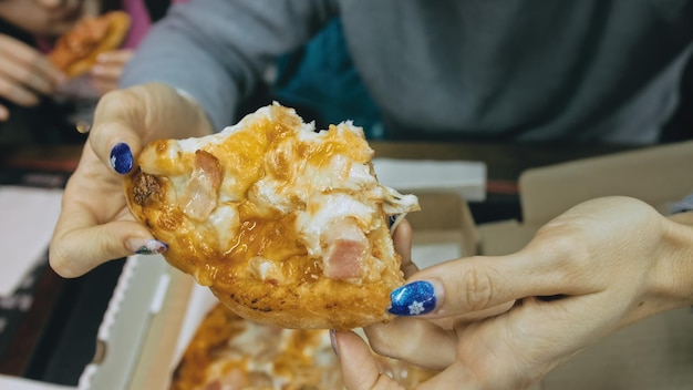 Mother and daughter eat pizza cheese four Close up of young woman eating pizza and chewing in outdoor restaurant Girl hands taking pieces slices of hot tasty italian pizza from open box