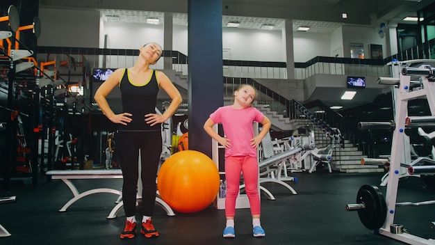 Mother and Daughter in the Gym Family Performs Physical doing Exercises Fitness Healthy Lifestyle Happy Sports Family Training Concept Woman with her Child doing Stretching Warmup in the Gym