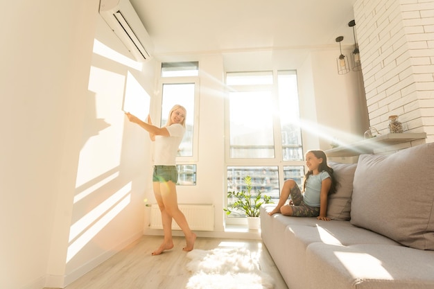 mother and daughter hangs a large photo canvas at home