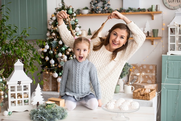 Mother and daughter have fun in Christmas kitchen at home.