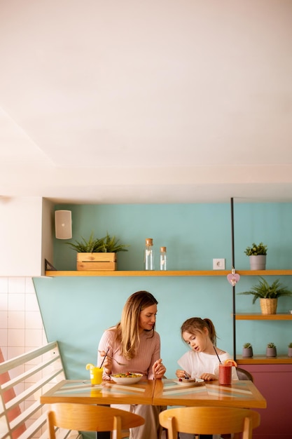 Mother and daughter having a breakfast with fresh squeezed juices in the cafe