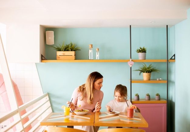 Mother and daughter having a breakfast with fresh squeezed juices in the cafe