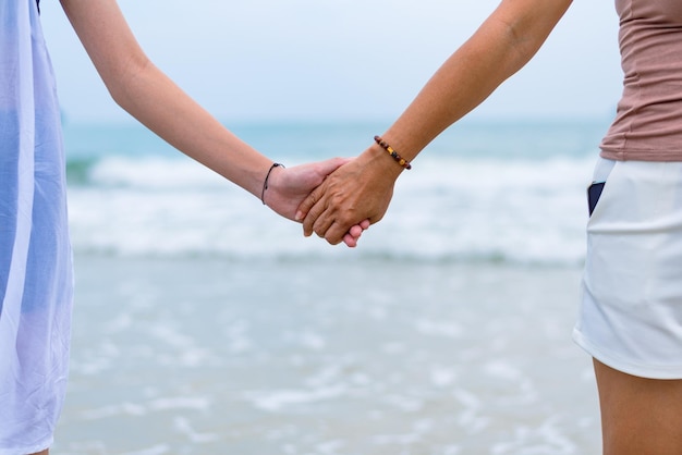 Mother and daughter holding hands on the beach