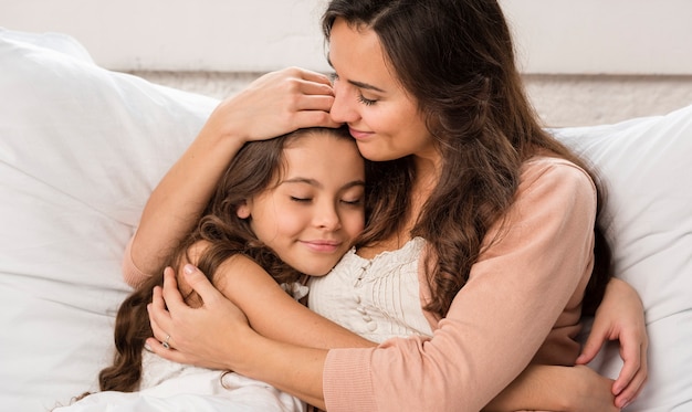 Mother and daughter hugging in bed