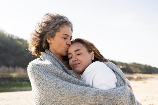 Mother and daughter hugging each other outdoors at the beach