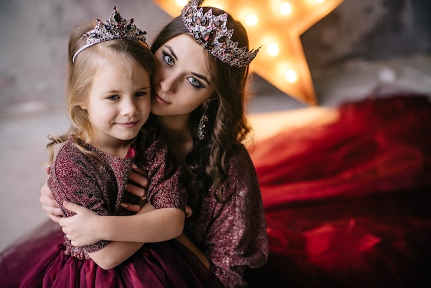 Mother and daughter in the image of the queen and princess dresses in the colors of Marsala with a long train in the loft